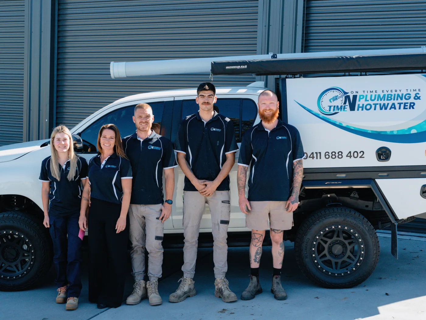 The On Time Plumbing & Hot Water team in front of a branded service ute